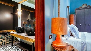 Una camera d'albergo moderna con un letto, un comodino e una lampada di legno di grandi dimensioni.