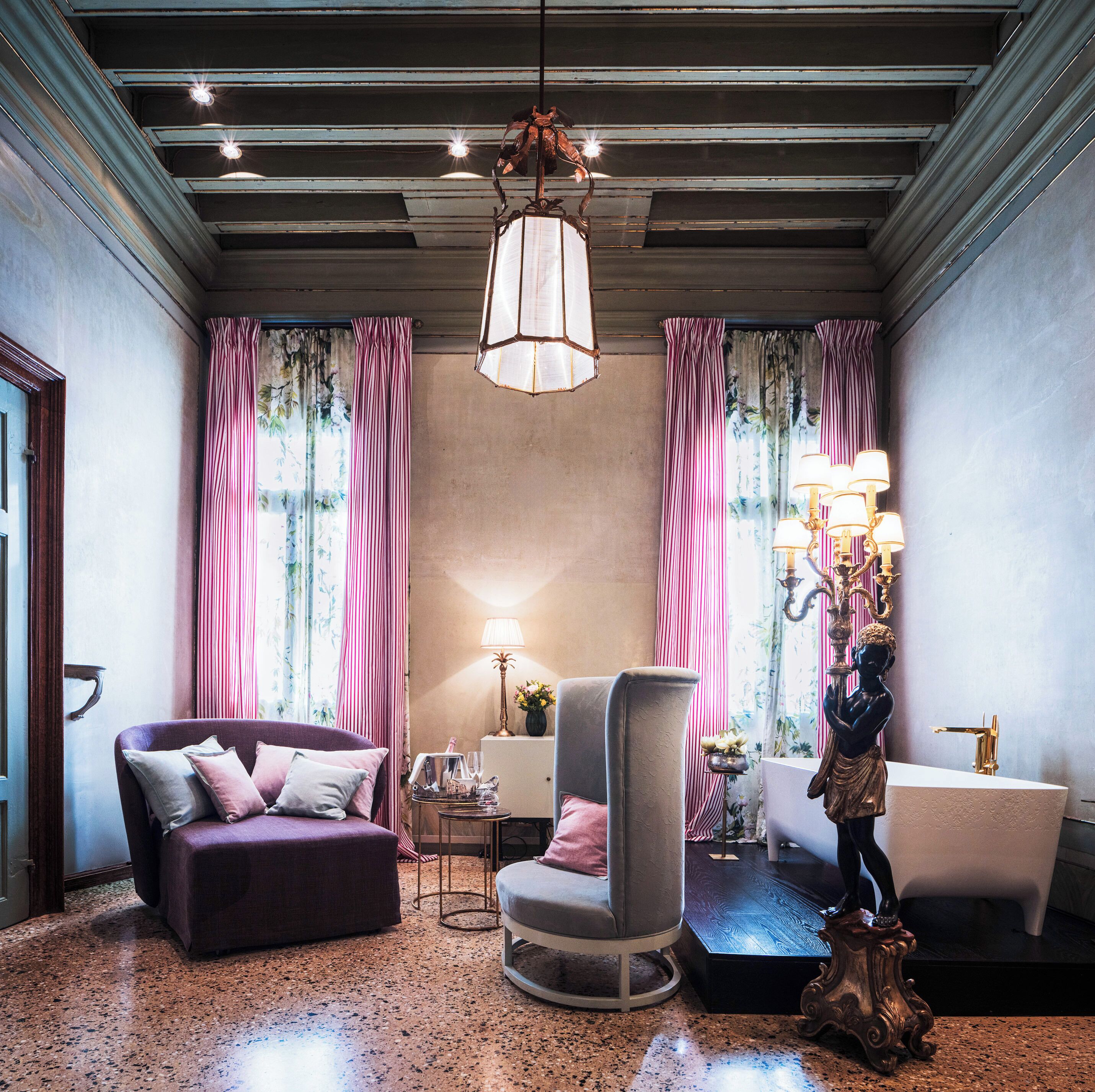 A room with a sofa, armchair, and a statue.