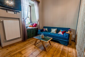 Ein gemütliches Wohnzimmer mit einem blauen Sofa, einem Holztisch und einer Heizung.