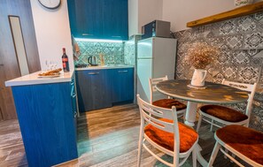 Eine moderne Küche mit blauen Schränken, einem weißen Kühlschrank und einem Essbereich mit rundem Tisch und Stühlen.