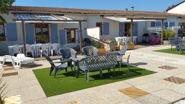 Un patio amueblado con mobiliario exterior, una parrilla y piso de baldosas de piedra.