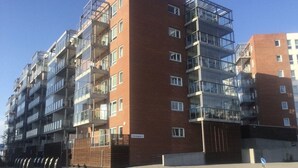 A multi-story residential building with balconies, a brick facade, and a gated entrance. - Gauk Apartments Sentrum 3 (Sandnes)
