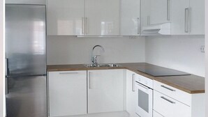 A modern kitchen with white cabinets, a stainless steel refrigerator, and a wooden countertop. - Gauk Apartments Sentrum 3 (Sandnes)