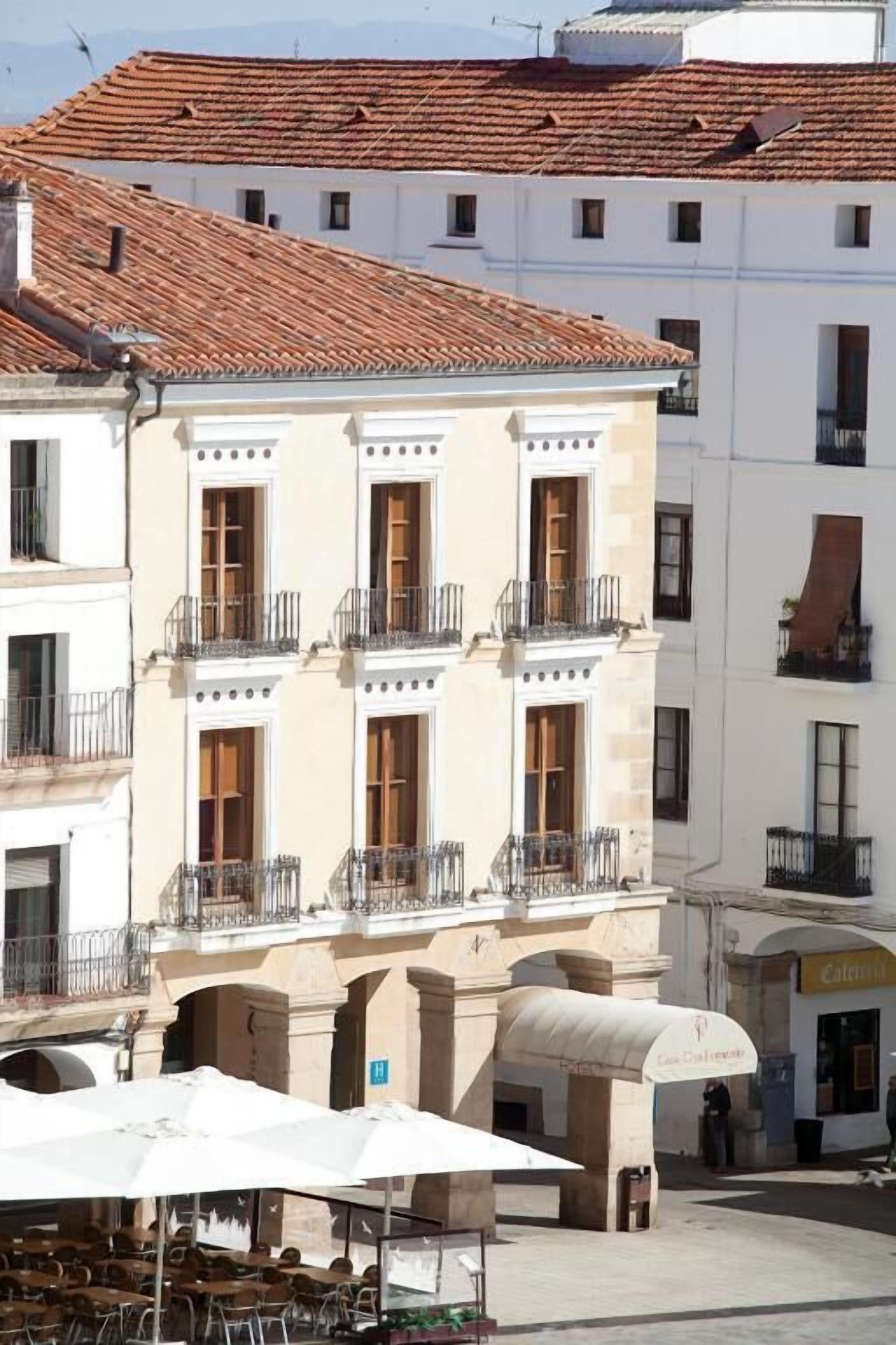 Un edificio con numerosi balconi e una zona caffè con posti a sedere all'aperto.