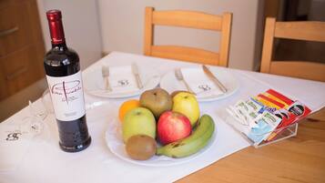 Una mesa con una botella de vino, platos de fruta y una cesta de aperitivos.
