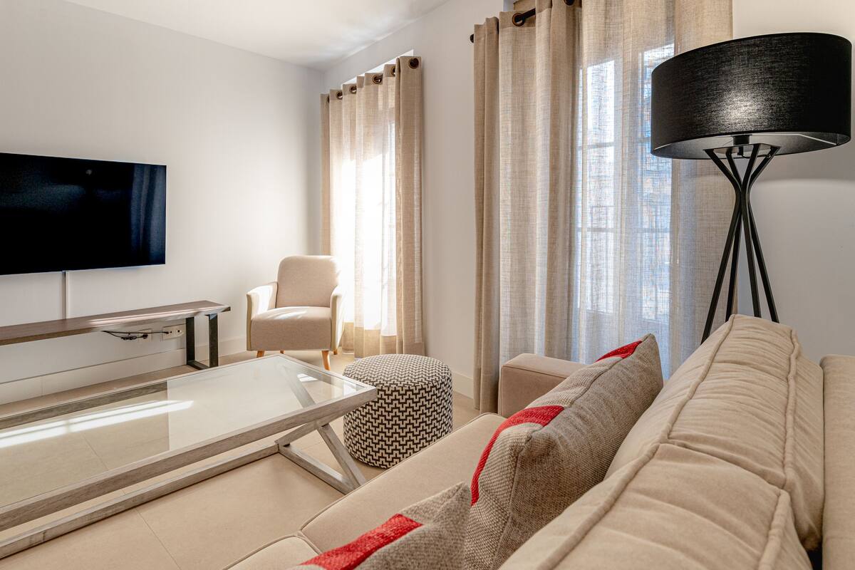 A modern living room with a flat-screen TV, a sofa, a coffee table, and a floor lamp.