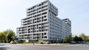 En modern, högre byggnad med ett rutmönstrat fasad, balkonger och ett platt tak.