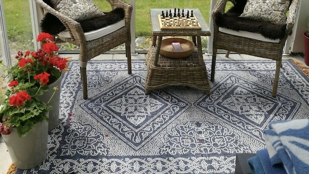A covered outdoor seating area with wicker chairs, a chess table, and a patterned rug. - Pulpit Rock Family Apartment (Sandnes)