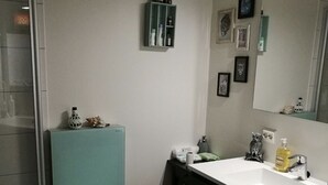 A compact bathroom with a white toilet, a sink with a mirror, and a small shelf with toiletries. - Pulpit Rock Family Apartment (Sandnes)