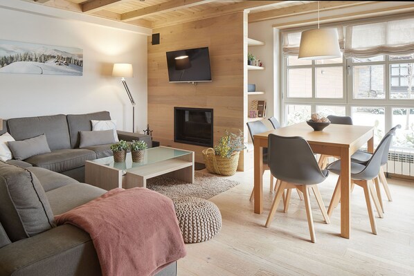 A modern living room with a sofa, coffee table, and dining area.