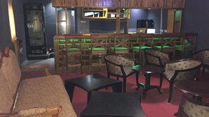 Une pièce comprenant un coin bar, plusieurs options d’assises, notamment des canapés et des fauteuils, ainsi qu’un écran de télévision.