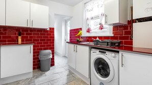 A modern kitchen with red and white tiles, a washing machine, and a window with curtains. - Fortified Home - Near Rochester Castle (Rochester)