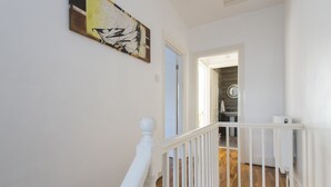 A staircase with white railings leading to a room with a wooden floor. - Fortified Home - Near Rochester Castle (Rochester)