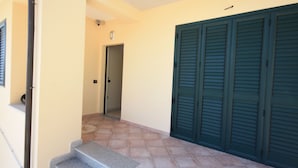 Ein Flur mit einer Treppe, die zu einem Zimmer führt, einer Tür und grünen Fensterläden.