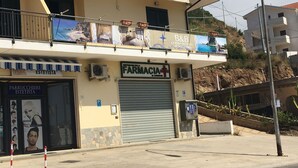 Ein Gebäude mit einer Apotheke im Erdgeschoss, einem Balkon mit Werbeanzeigen und einem Parkschild.