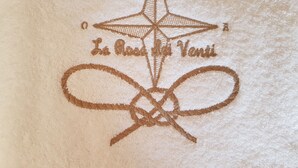 Ein Detailaufnahme eines strukturierten Stoffes mit geometrischem Muster und eingesticktem Text.