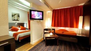 Habitación de hotel con dos camas, televisor, escritorio y cortina roja.