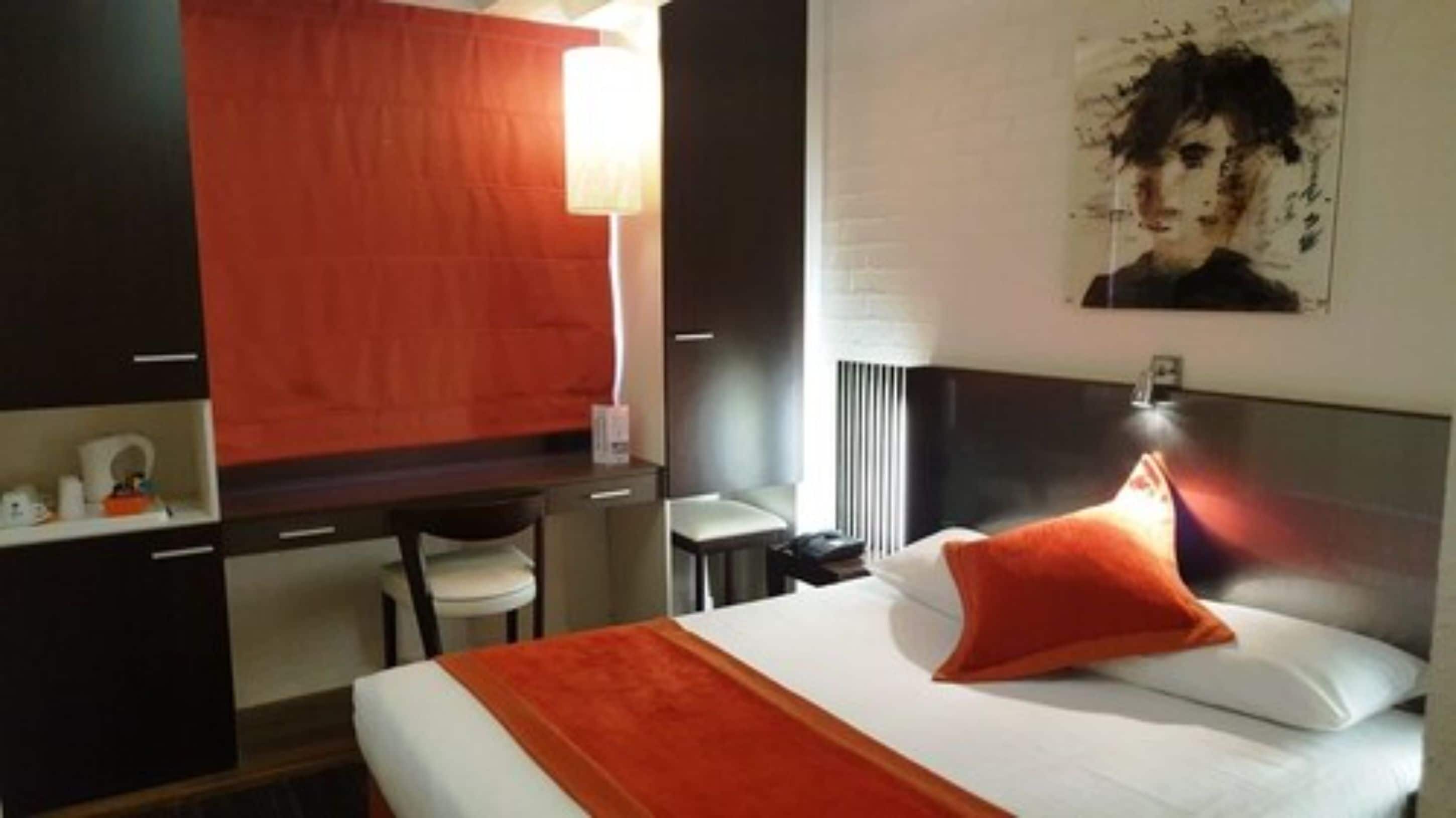 Una habitación de hotel con una cama, un escritorio y una silla.