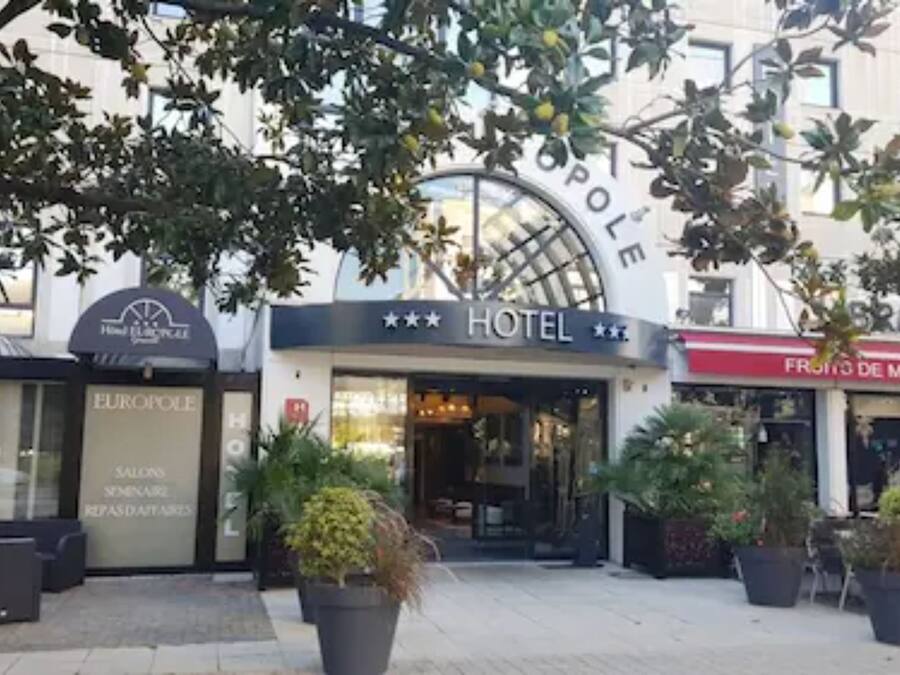 Un hotel con un letrero llamativo, terraza al aire libre y plantas en macetas.