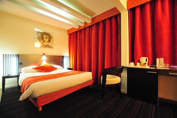 A hotel room with a bed, a desk, a chair, and a large window with curtains. - Hôtel Europole (Grenoble)