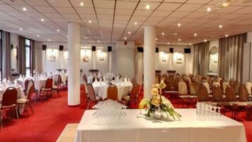 Un salón de banquetes con mesas redondas dispuestas para comer, manteles blancos y sillas.