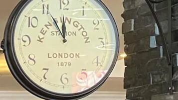 A large wall-mounted clock with the brand 'KENINGTON' and the year '1879' visible, indicating its vintage style.