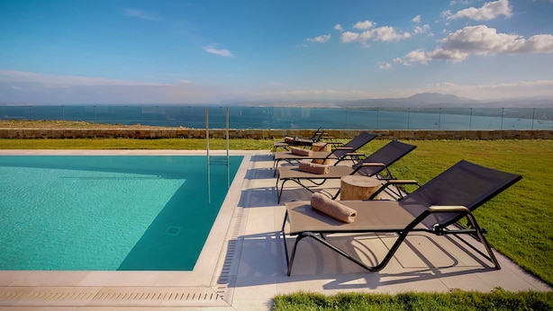 A swimming pool with lounge chairs and a view of the ocean and mountains. - Ocean Villas Complex by Ocean Residences (Malevizi)