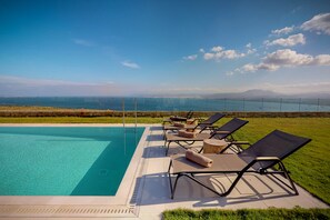 A swimming pool with lounge chairs and a view of the ocean and mountains. - Ocean Villas Complex by Ocean Residences (Malevizi)
