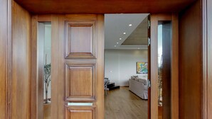 A wooden door leading into a room with a wooden floor, a white sofa, and a painting on the wall. - Ocean Villas Complex by Ocean Residences (Malevizi)