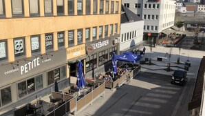 A street view with a yellow building housing a restaurant named 'PETITE' and a bar named 'BONDENES HUS'. - Gauk Apartments Sentrum 4 (Sandnes)