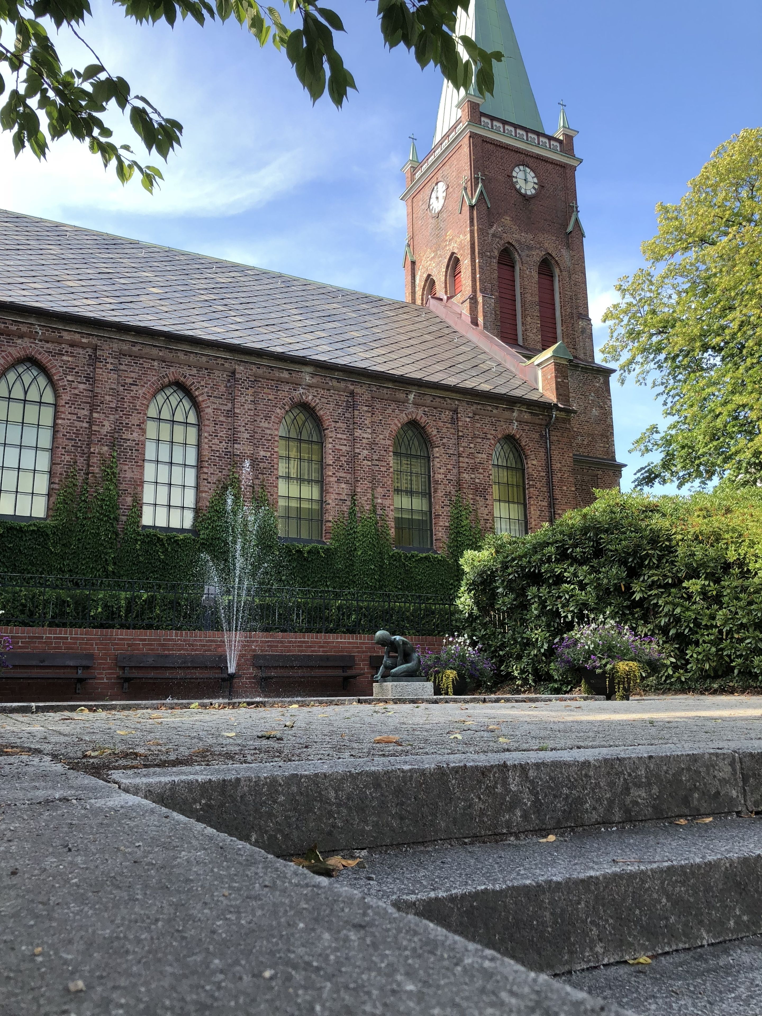 A church with a clock tower, arched windows, and a fountain.