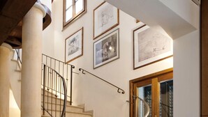 A spiral staircase with a metal railing, leading to a landing with framed artwork on the walls. - Assia Spa (Fucecchio)