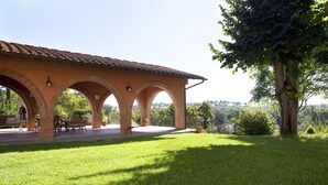 A covered outdoor area with arches, a lawn, and a tree. - Assia Spa (Fucecchio)