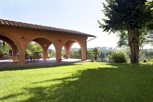 Un espacio al aire libre cubierto con arcos, césped y un árbol.