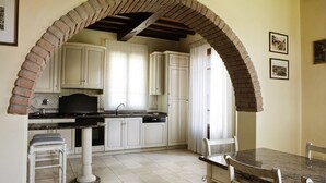 A kitchen with white cabinets, a granite countertop, and a brick archway. - Assia Spa (Fucecchio)