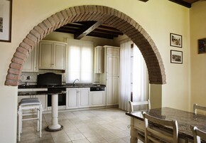 Una cocina con armarios blancos, encimera de granito y un arco de ladrillo.