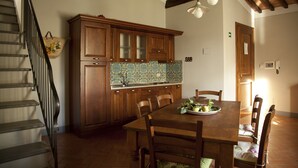 A kitchen with wooden cabinets, a tiled backsplash, and a dining table set for four. - Agriturismo La Colombaia (Cerreto Guidi)