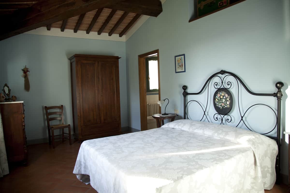 Een slaapkamer met een bed, een houten garderobe en een stoel.