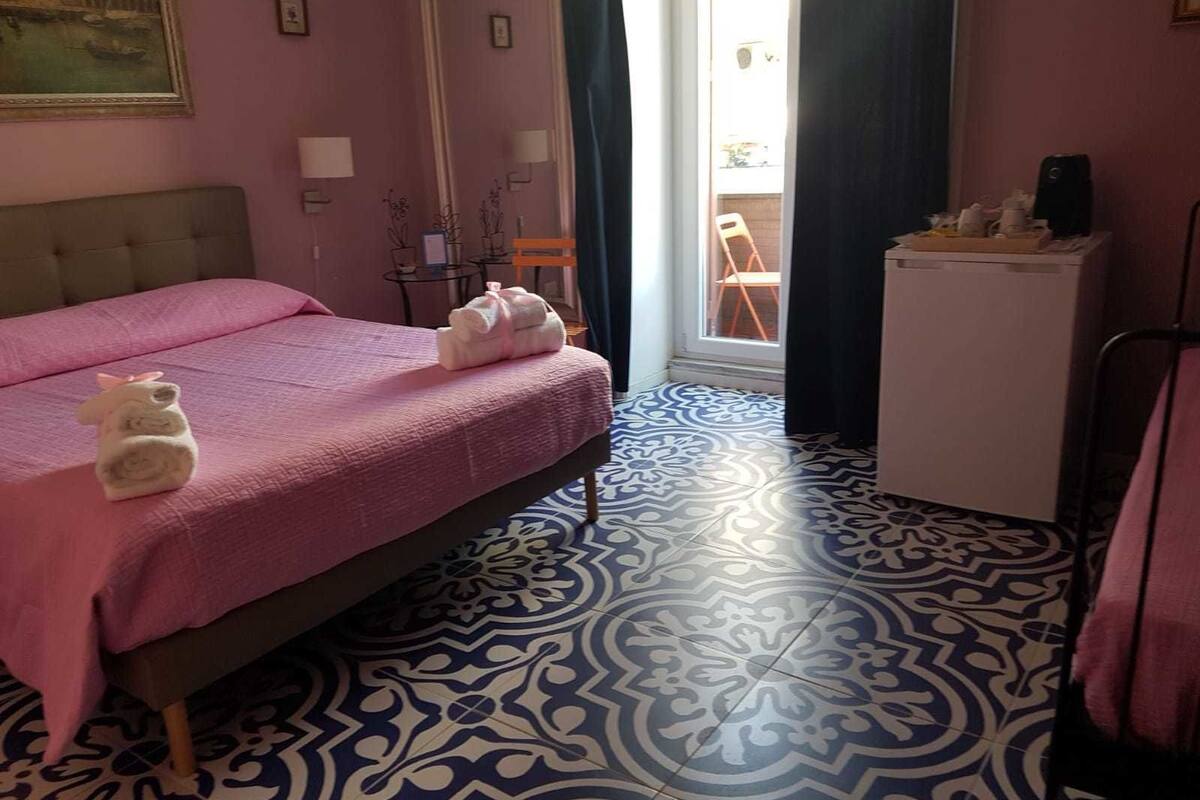 Une pièce comprenant un lit, une petite table, une chaise et une fenêtre avec des rideaux.