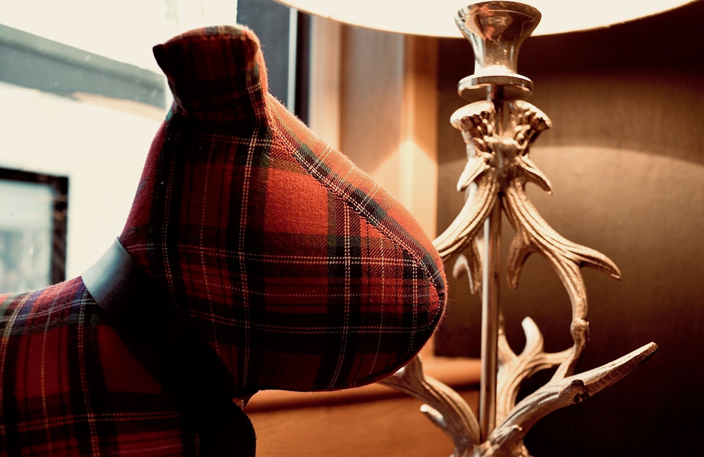 Un article en tissu à carreaux, peut-être un coussin ou une couverture, placé à côté d’un support métallique décoratif.