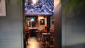Un espacio interior acogedor con mesas y sillas de madera, una mesa de billar y un adorno de cabeza de ciervo montado en la pared.