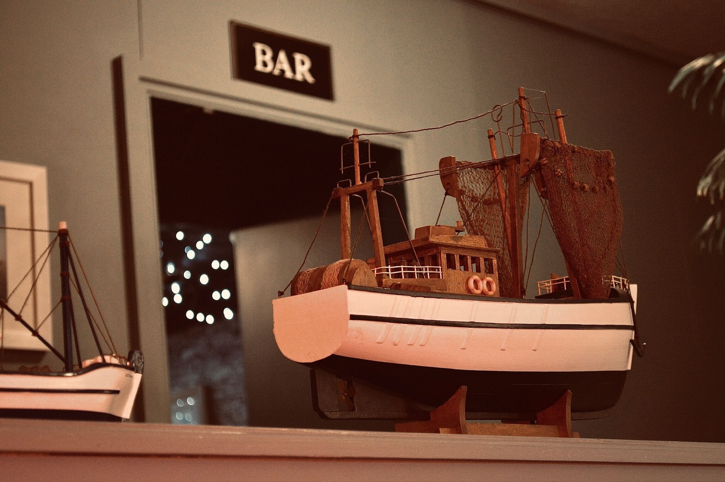 A model ship on display with a sign reading "BAR" in the background.