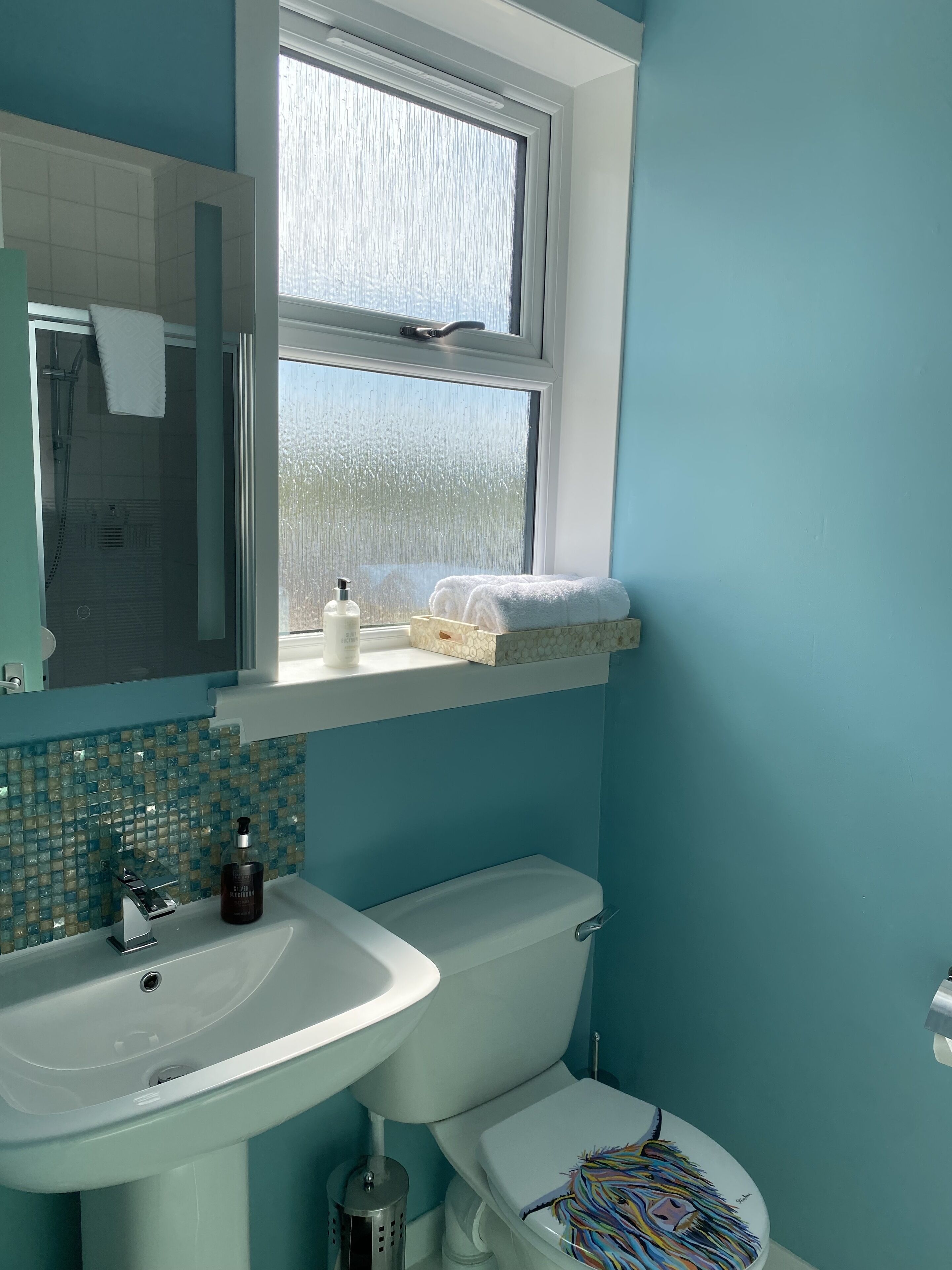 A bathroom with a sink, toilet, and window.