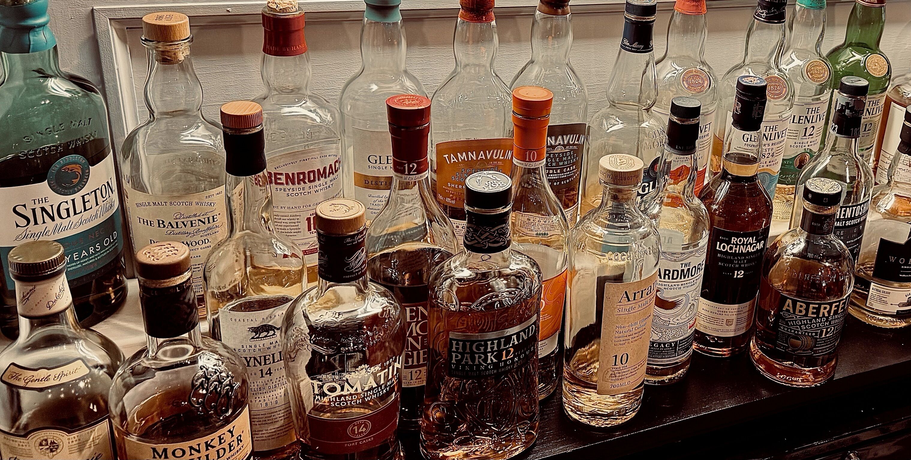 Verschillende flessen whisky staan op een plank.
