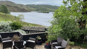 Terraza con mobiliario de mimbre con vista a un lago y colinas.