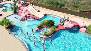 A large outdoor swimming pool with a water slide, a small waterfall, and a river running alongside. - Camping Tikayan La Vallée du Paradis (Saint-Raphael)