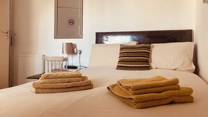 A hotel room with a neatly made bed, a chair, a lamp, and a no-smoking sign on the wall. - The Haven Guest House (Holyhead)