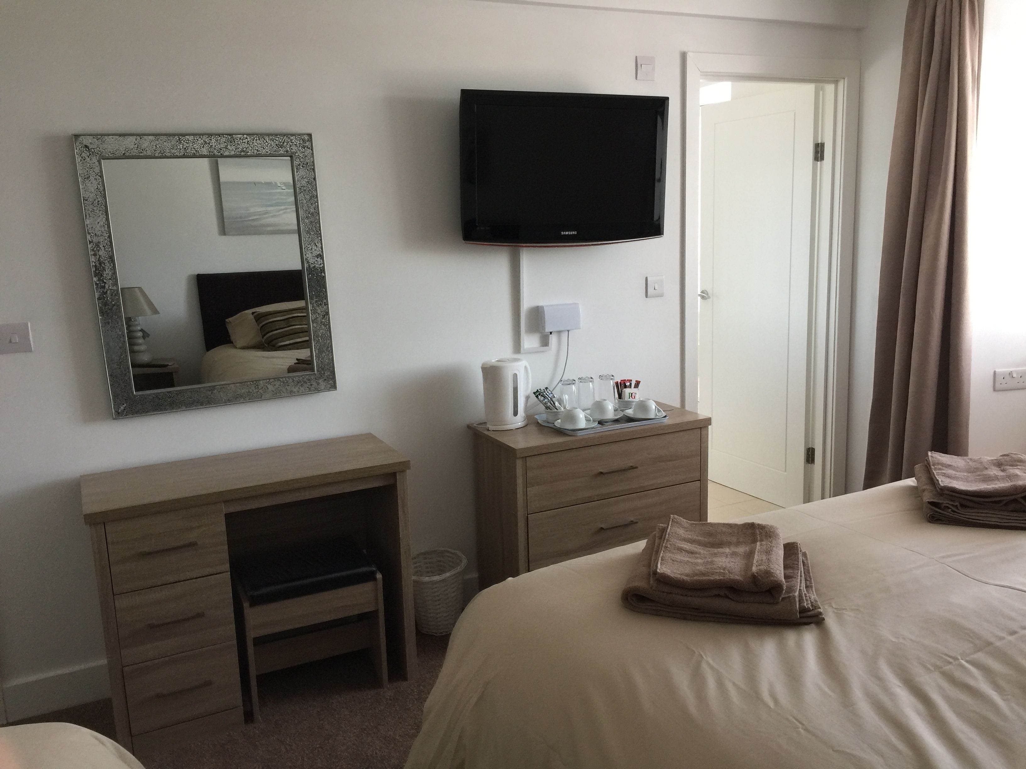 A hotel room with a bed, a desk, a television, and a mirror.