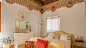 A bedroom with a bed, bedside table, dresser, and a decorative ceiling. - Benedetto Duomo (Florence)