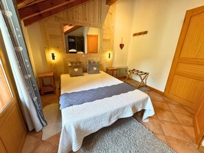 A cozy bedroom with a large bed, wooden walls, a mirror, and a small table.